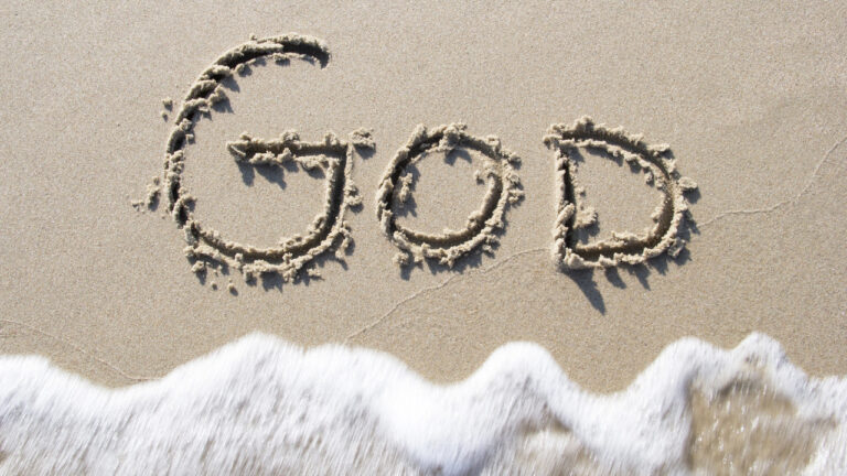 Beach scene with "GOD" written in sand, symbolizing faith and divine timing.